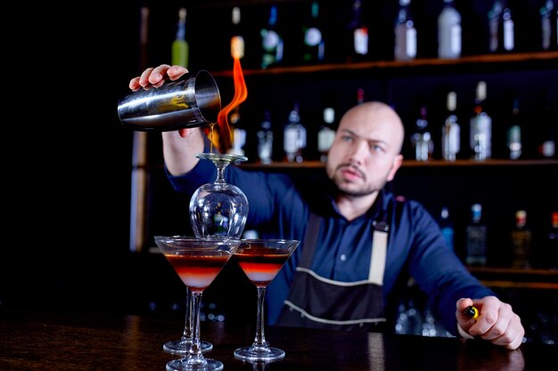 Spettacolo infuocato al bar. Il barista prepara un cocktail alcolico caldo e accende il bar. Il barista prepara un cocktail infuocato. Fuoco sulla barra.