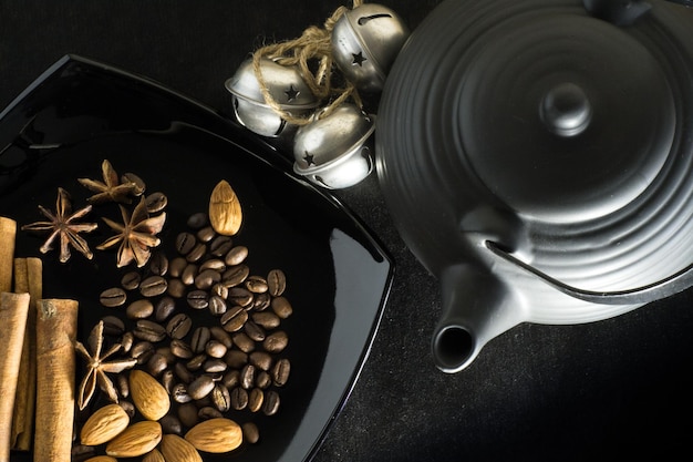 Spezie di chicchi di caffè con una teiera e campane su sfondo nero