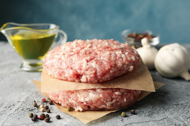 Spezie e carta da forno con carne tritata su grigio, da vicino