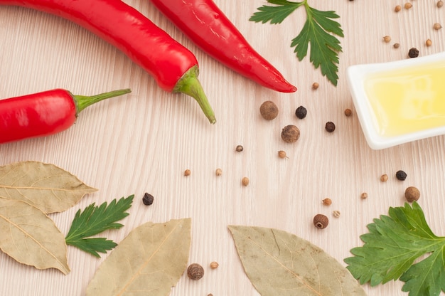 Spezie, prezzemolo, olio d'oliva e peperoncino su un tavolo in legno