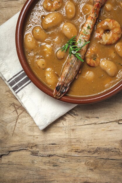 Spezzatino di fagioli bianchi fatti in casa tradizionale con gamberi. Cucina tipica spagnola. sulla tavola di legno