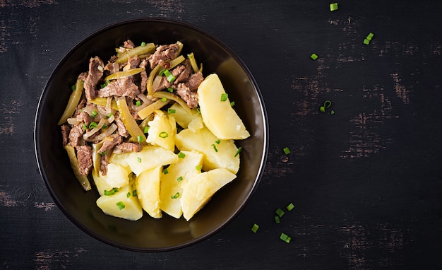 Spezzatino di manzo, pezzi di manzo in umido con cetriolo sottaceto in stile russo. Stroganoff di manzo e patate lesse. Vista dall'alto, in alto, piatto