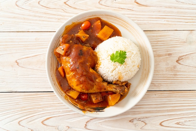 spezzatino di pollo fatto in casa con pomodori, cipolle, carote e patate su piatto con riso