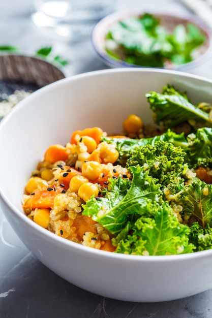 Spezzatino vegano con ceci, patate dolci e cavolo nero in una ciotola bianca.