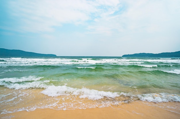 Spiaggia bianca sabbia blu oceano acqua e verde lussureggiante giungla tropicale piccole isole verdi all'orizzonte