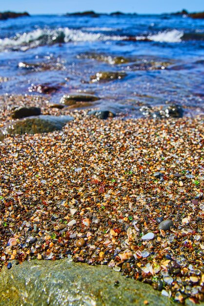 Spiaggia con onde e piena di pezzi lisci di vetro colorato