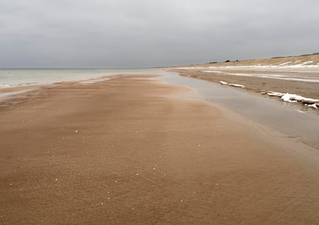 Spiaggia d'inverno sulla penisola di Curonian con tempo nuvoloso in Lituania