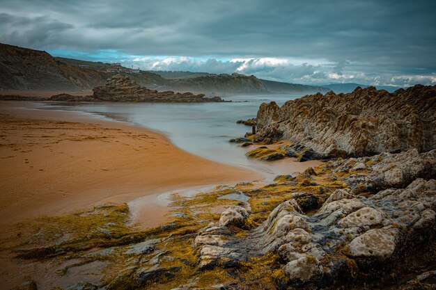 SPIAGGIA DEL NORD CON ONDE E ROCCE SOTTO CIELI NUVOLI DI PRIMAVERA