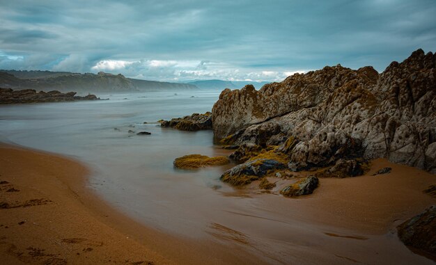 SPIAGGIA DEL NORD CON ONDE E ROCCE SOTTO CIELI NUVOLI DI PRIMAVERA