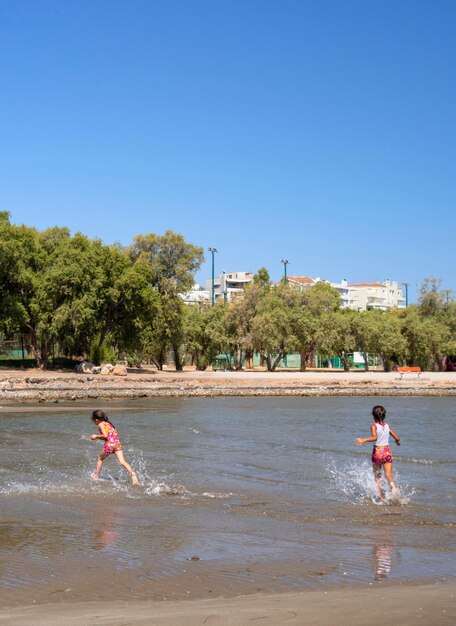 Spiaggia della città e bambini che giocano nel mare in Grecia