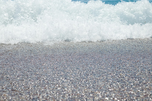 Spiaggia di ciottoli con acqua di mare azzurra sullo sfondo di texture Acqua di mare limpida su una spiaggia di ciottoli acqua pura sulla costa di pietracon costa lapidata splendida vista sul marevacanze nel paradiso estivo