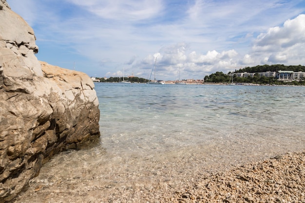 Spiaggia di ghiaia con rocce sull'acqua limpida della costa croata