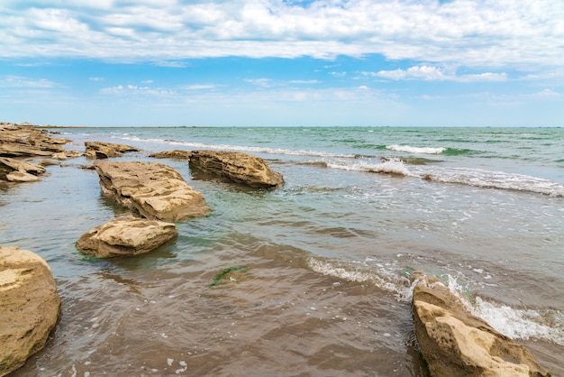 Spiaggia di mare rocciosa vuota con piccole onde