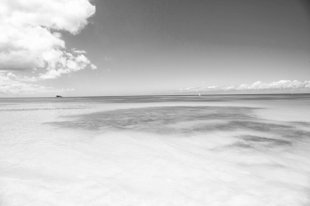 Spiaggia di sabbia bianca con acqua di mare azzurra e cristallina e cielo blu con nuvole sullo sfondo naturale di una giornata di sole