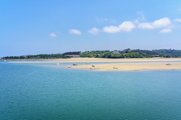 Spiaggia di sabbia bianca con piccole barche e cielo azzurro in estate