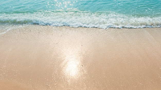 Spiaggia di sabbia blu di riflessione di luce solare delle onde di oceano