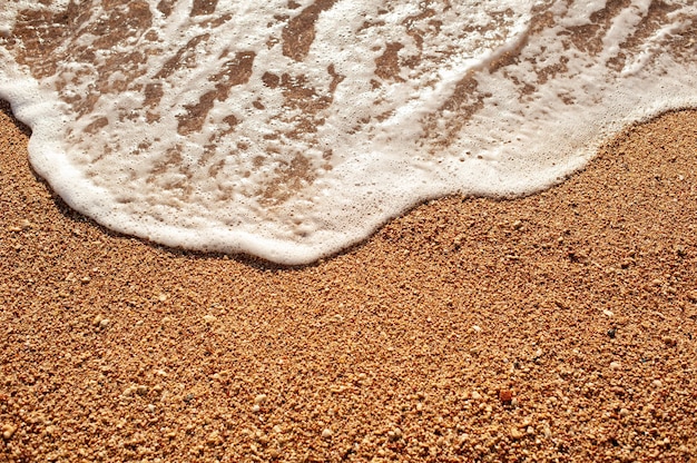 Spiaggia di sabbia di mare con onda e sfondo estivo schiumoso bianco, spiaggia aerea vista dall'alto mare sopraelevato.