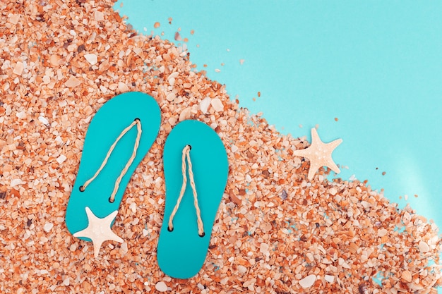 Spiaggia di sabbia e pantofole estive con piccole stelle marine
