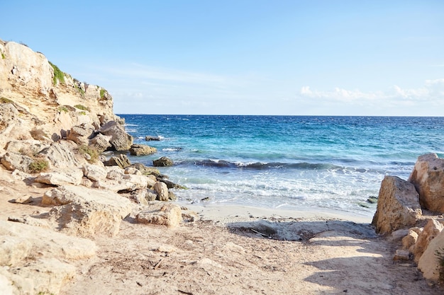 spiaggia di sabbia mare estivo con cielo blu acqua del mare con rocce verdi e onde bianche un bellissimo paesaggio marino