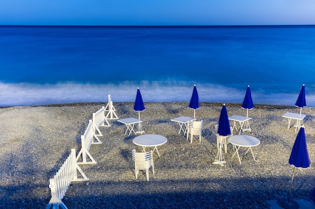 Spiaggia notturna con ombrelloni tavoli e sedie