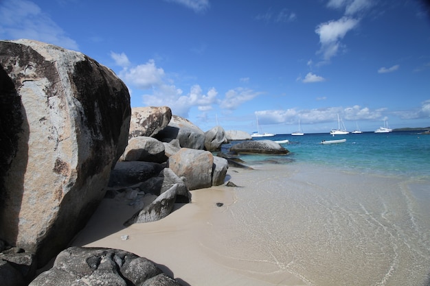 Spiaggia paradisiaca e solitaria con grandi scogli e sabbia fine