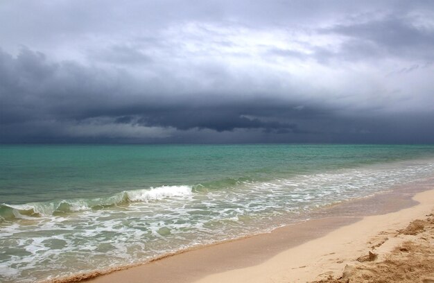 Spiaggia prima di un temporale mare blu calmo e cielo nuvoloso scuro