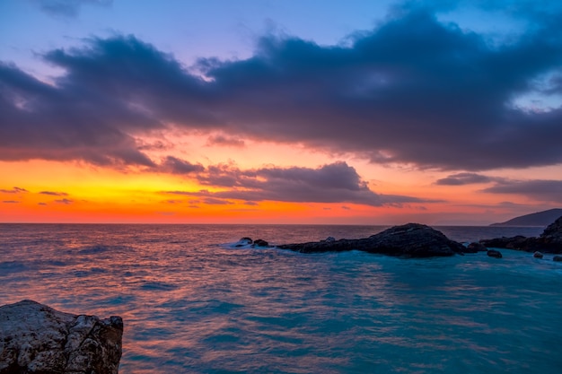 Spiaggia rocciosa. Tante nuvole nel cielo e colori incredibili fino all'alba