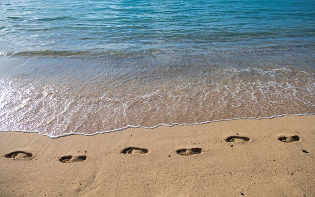 Spiaggia tropicale di sabbia con onde del mare. Passi sulla riva. Ritmi di orme nella sabbia al tramonto.