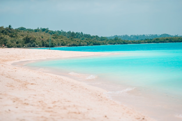 Spiaggia tropicale idilliaca nei Caraibi con sabbia bianca, acqua dell'oceano turchese e cielo blu