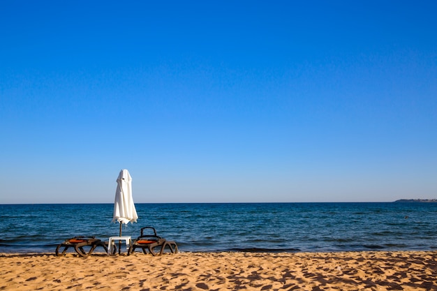 Spiaggia vuota con lettino e ombrellone chiuso.