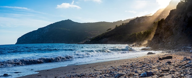 Spiaggia vuota in Toscana Italia Baia di sabbia nel parco naturale costa drammatica promontorio roccioso pineta mare mediterraneo blu sventolando l'acqua