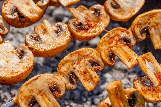 Spiedini di barbecue con delizioso kebab di funghi champignon alla griglia in un braciere