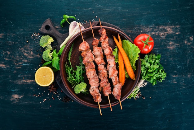 Spiedini di carne al forno su un piatto su uno sfondo di legno Vista dall'alto Copia spazio