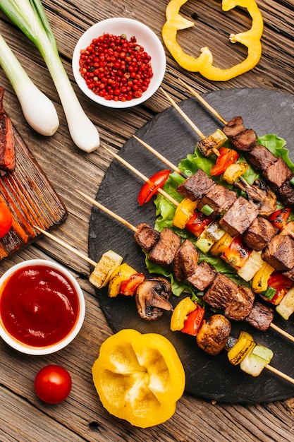 Spiedini di carne alla griglia con verdure sul tavolo di legno