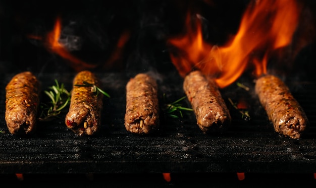 Spiedini di carne di agnello alla griglia alla griglia con fiamme di fuoco strofinare l'agnello sulla griglia del barbecue
