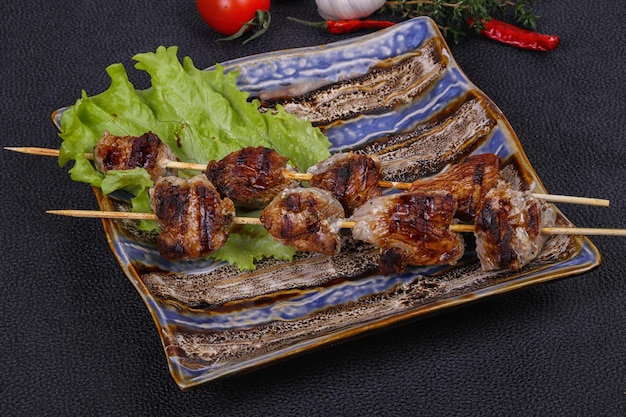 Spiedini di kebab di maiale nel piatto con foglie di insalata e pomodori