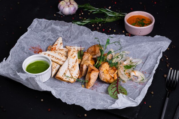 Spiedini di pollo con burro verde e pita alla griglia su una superficie scura