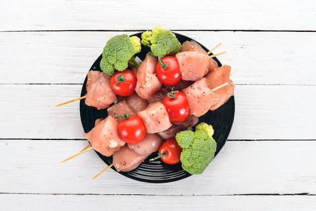 Spiedini di pollo crudo con pomodori e verdure Kebab su sfondo di legno Vista dall'alto Spazio di copia