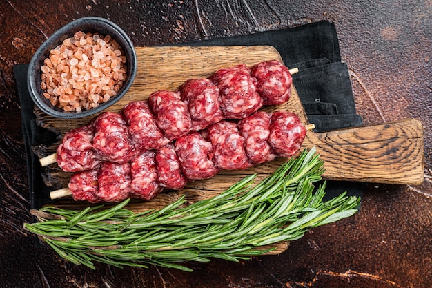 Spiedini di shish kebab tradizionale crudo con carne di manzo e spezie Sfondo scuro Vista dall'alto