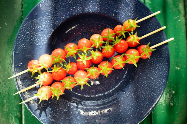 Spiedino di pomodori Pachino rossi su piatto blu