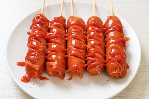 spiedino di salsiccia fritta con ketchup sul piatto bianco