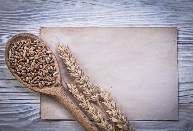 Spighe di grano di segale raccolto di mais cucchiaio di legno foglio di carta vintage su tavola di legno concetto di cibo e bevande