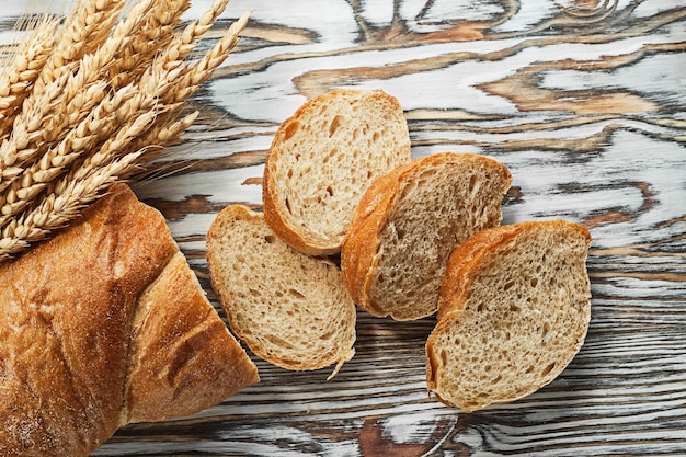 Spighe di segale mature del pane affettato su superficie di legno