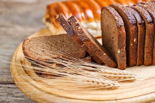 Spighette del grano e del pane su un fondo di legno