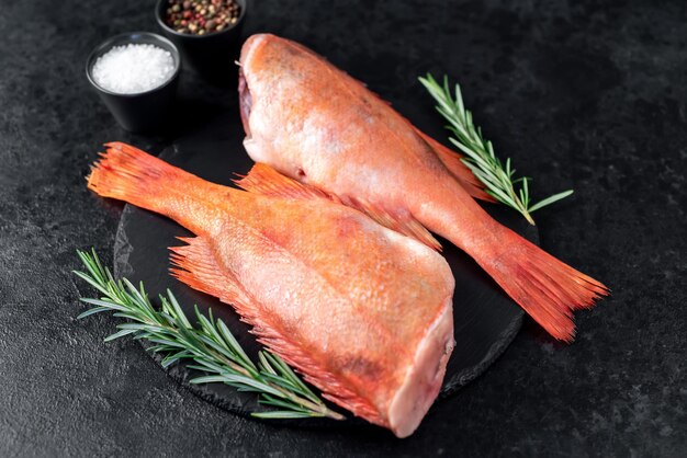 Spigola rossa cruda con rosmarino e spezie su fondo di pietra