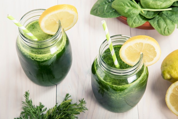 Spinaci con succo di limone un barattolo di bibite con paglia su un tavolo di legno bianco