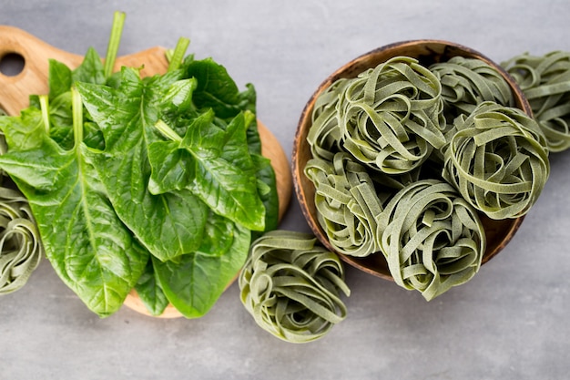 Spinaci freschi con pasta verde su sfondo grigio.