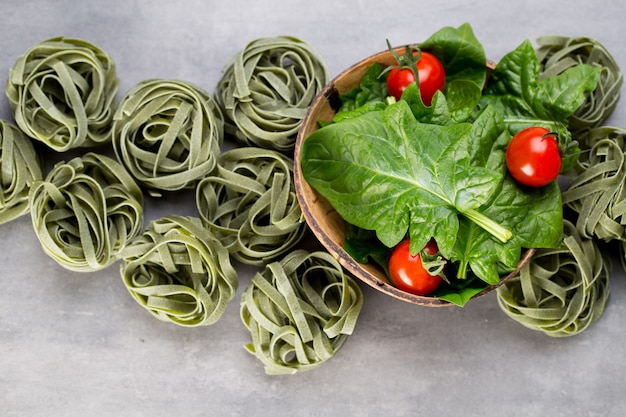 Spinaci freschi con pasta verde su un grigio