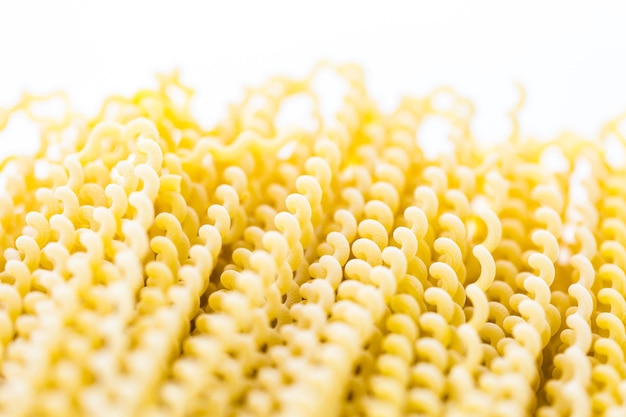 Spirali di pasta lunga gialla organica su sfondo bianco.