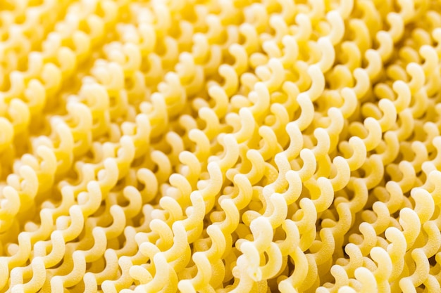 Spirali di pasta lunga gialla organica su sfondo bianco.